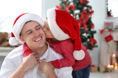 Father and child in Santa hats celebrating Christmas at home