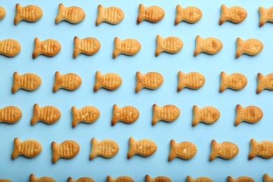 Photo of Delicious goldfish crackers on light blue background, flat lay