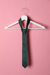 Photo of Hanger with black tie on pink background