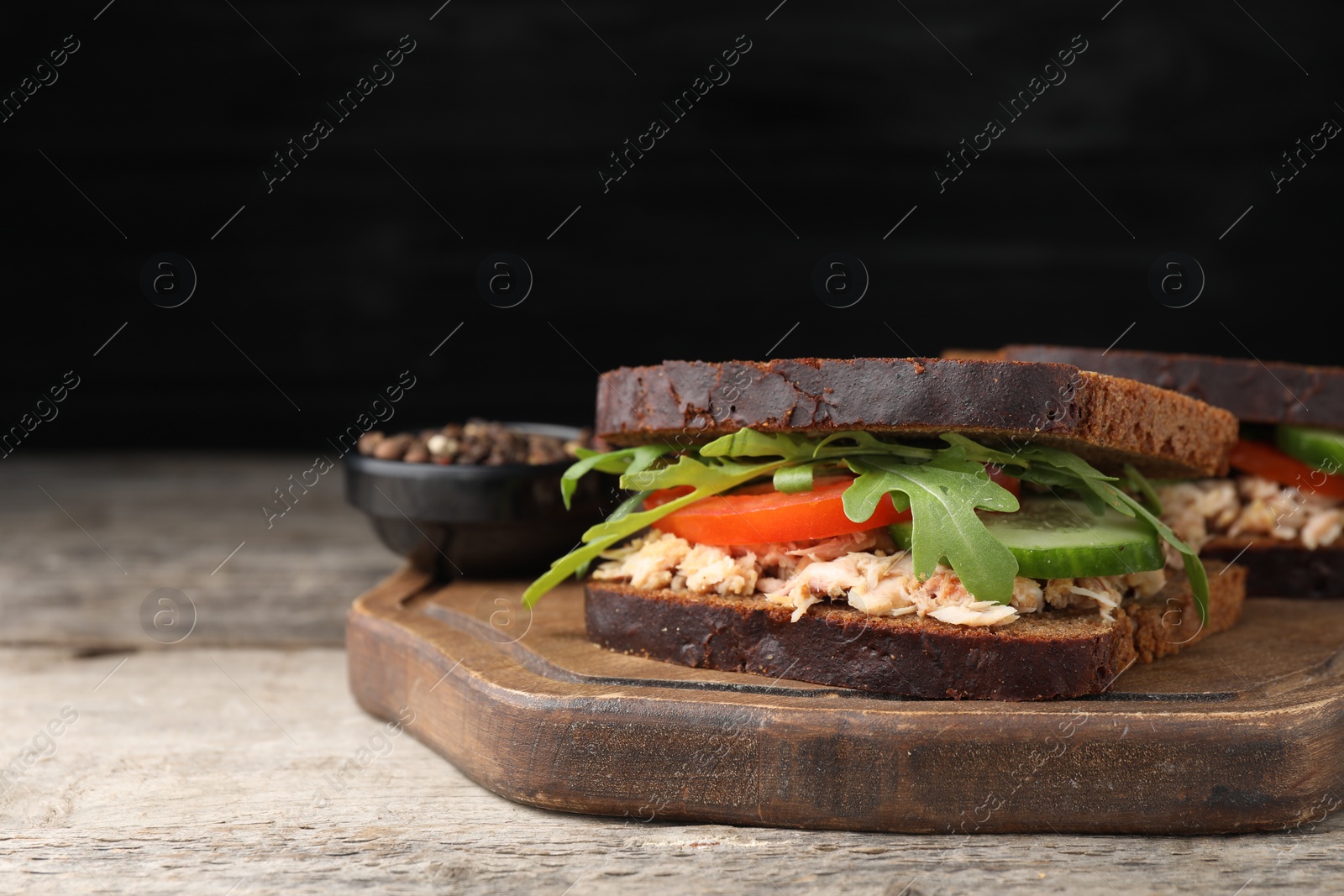 Photo of Delicious sandwiches with tuna and vegetables on wooden table, space for text