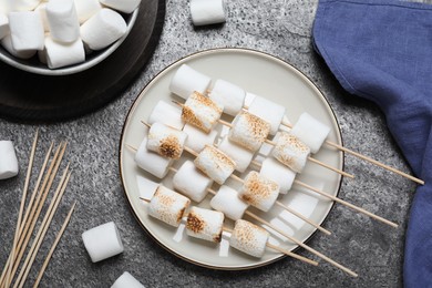 Photo of Sticks with roasted marshmallows on grey table, flat lay