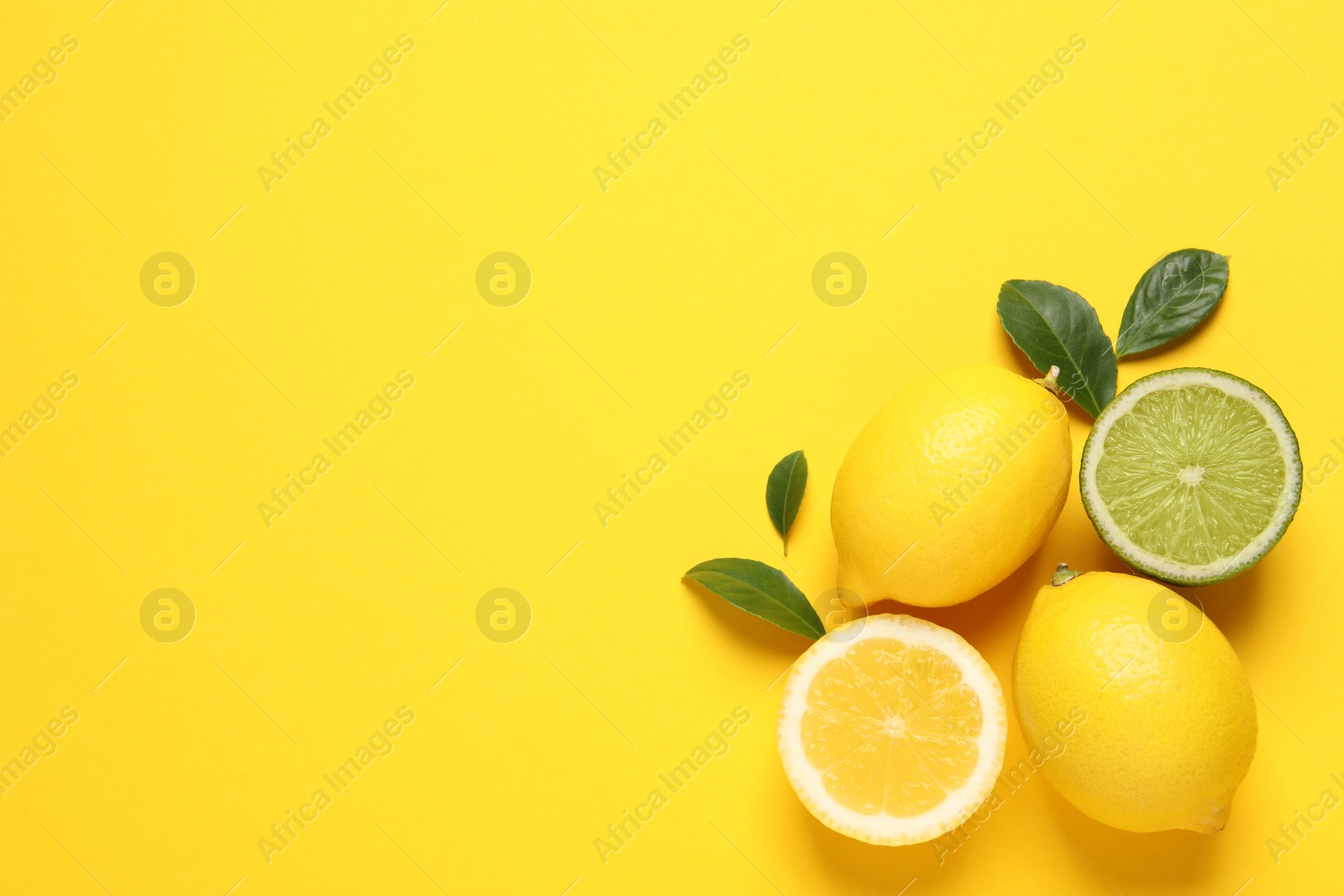 Photo of Fresh ripe lemons, lime and green leaves on yellow background, flat lay. Space for text