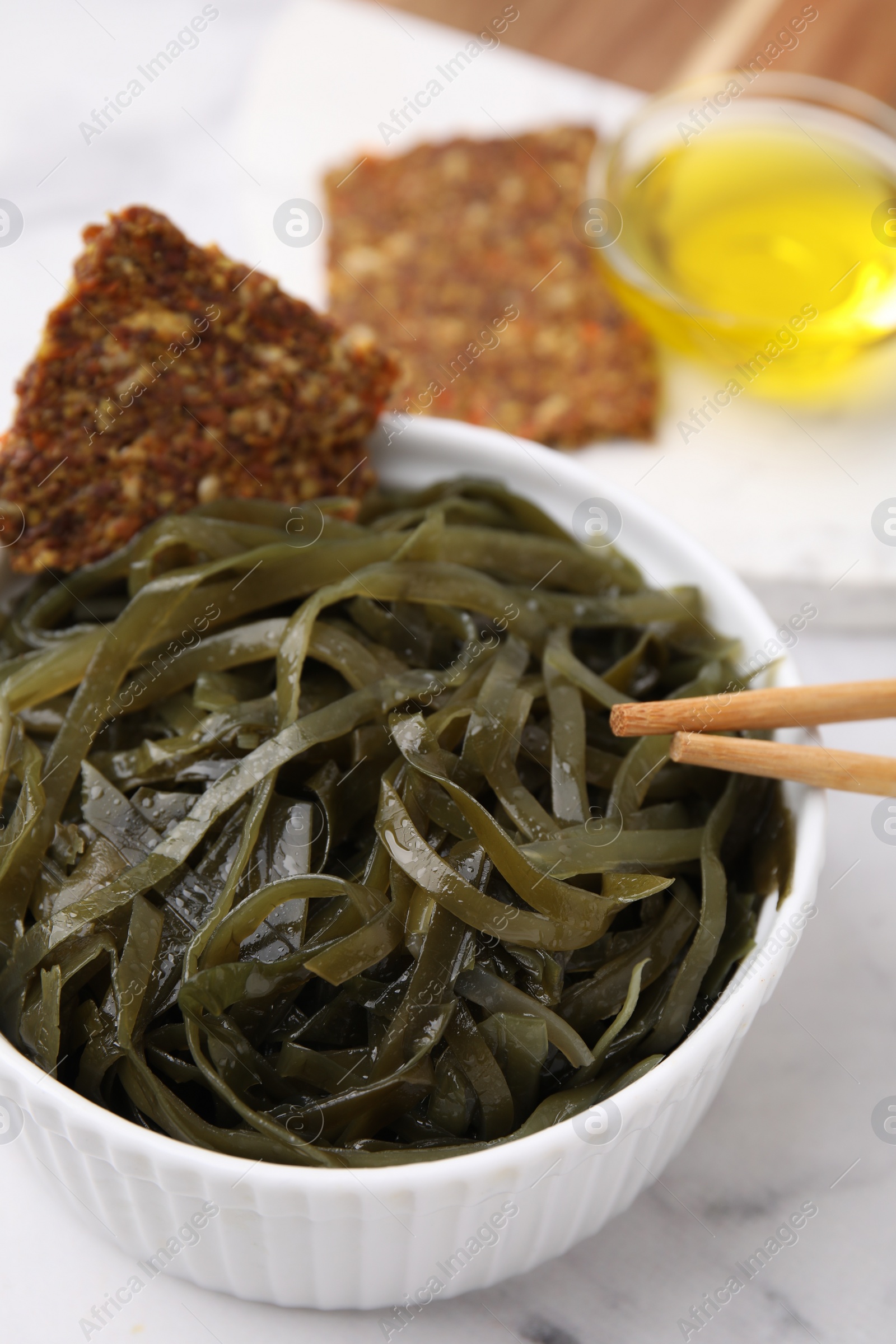 Photo of Tasty seaweed salad in bowl served on white table, closeup