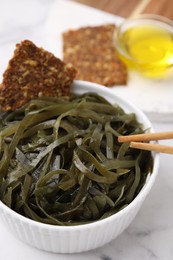 Tasty seaweed salad in bowl served on white table, closeup