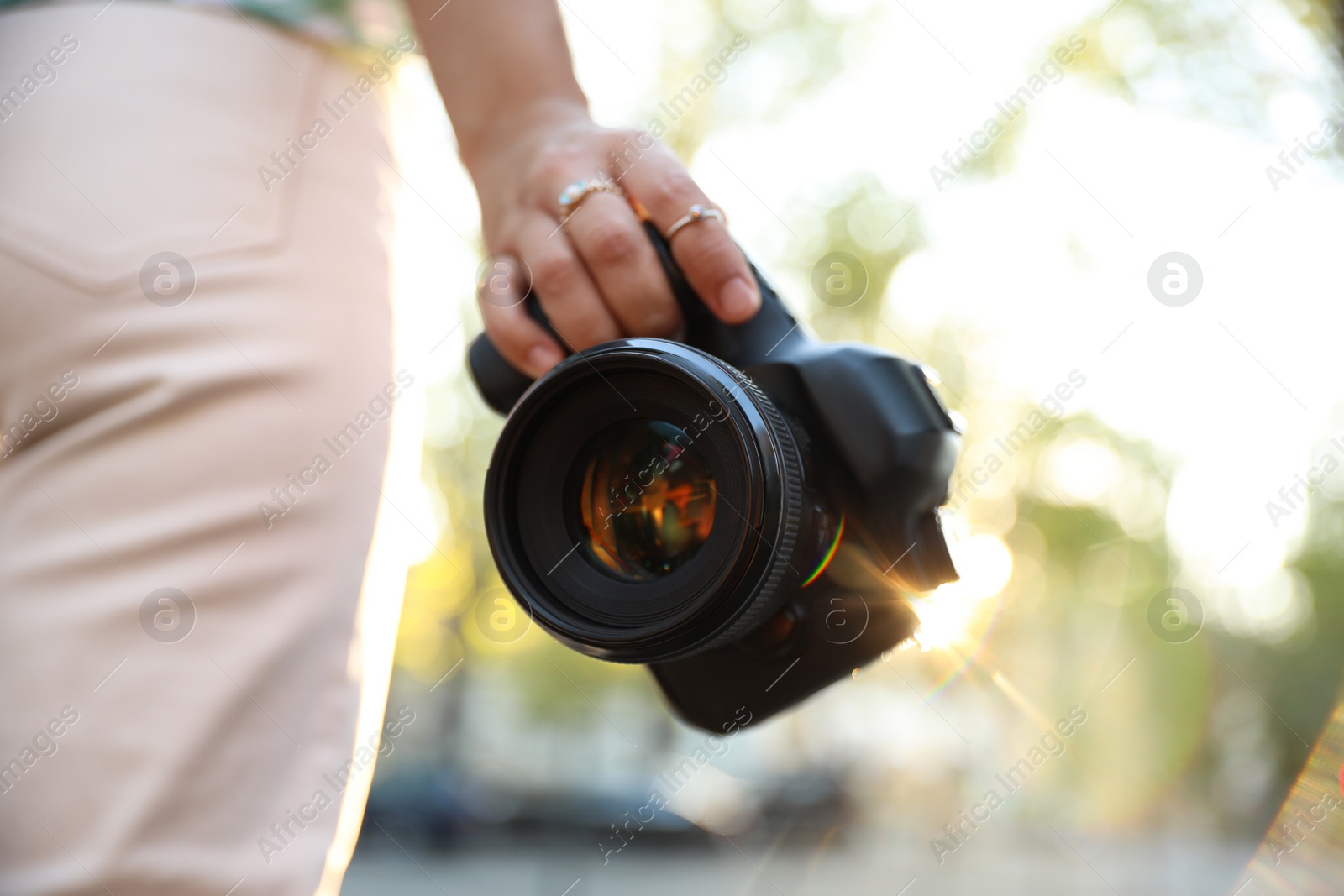 Photo of Young photographer with professional camera outdoors, closeup