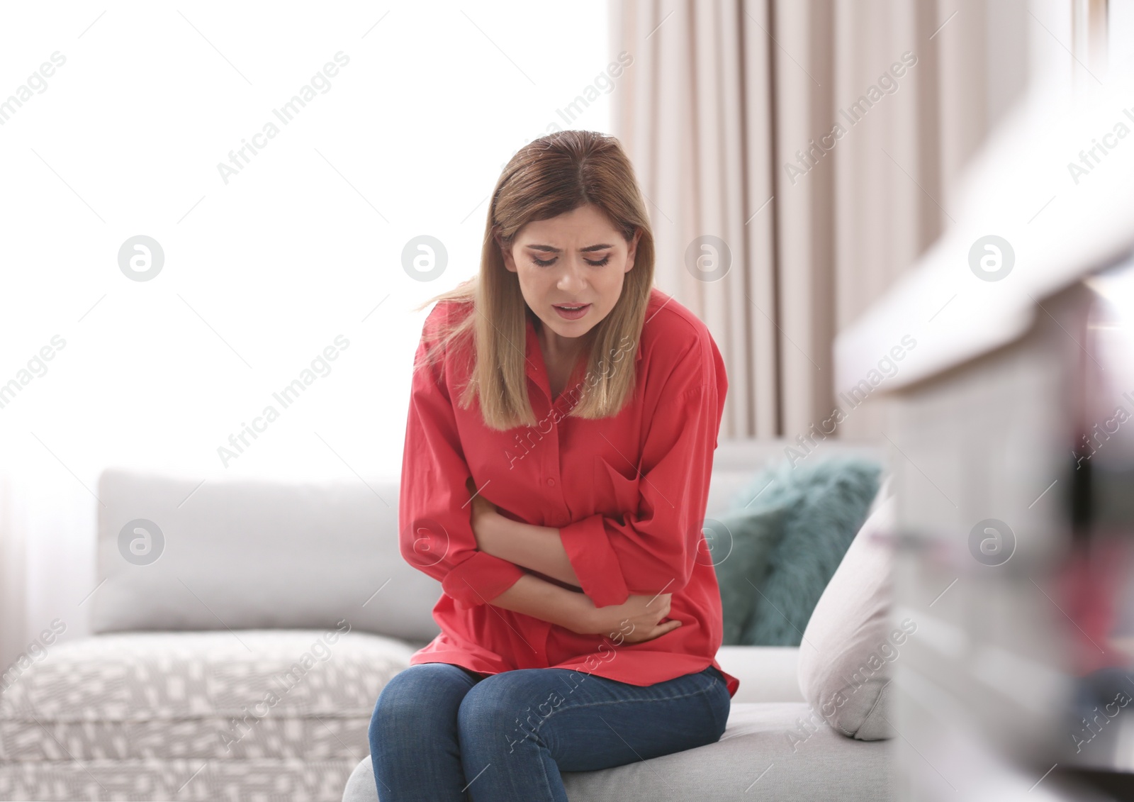 Photo of Young woman suffering from stomach ache at home