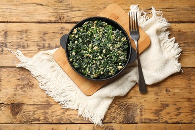 Photo of Tasty spinach dip with eggs in dish served on wooden table, top view