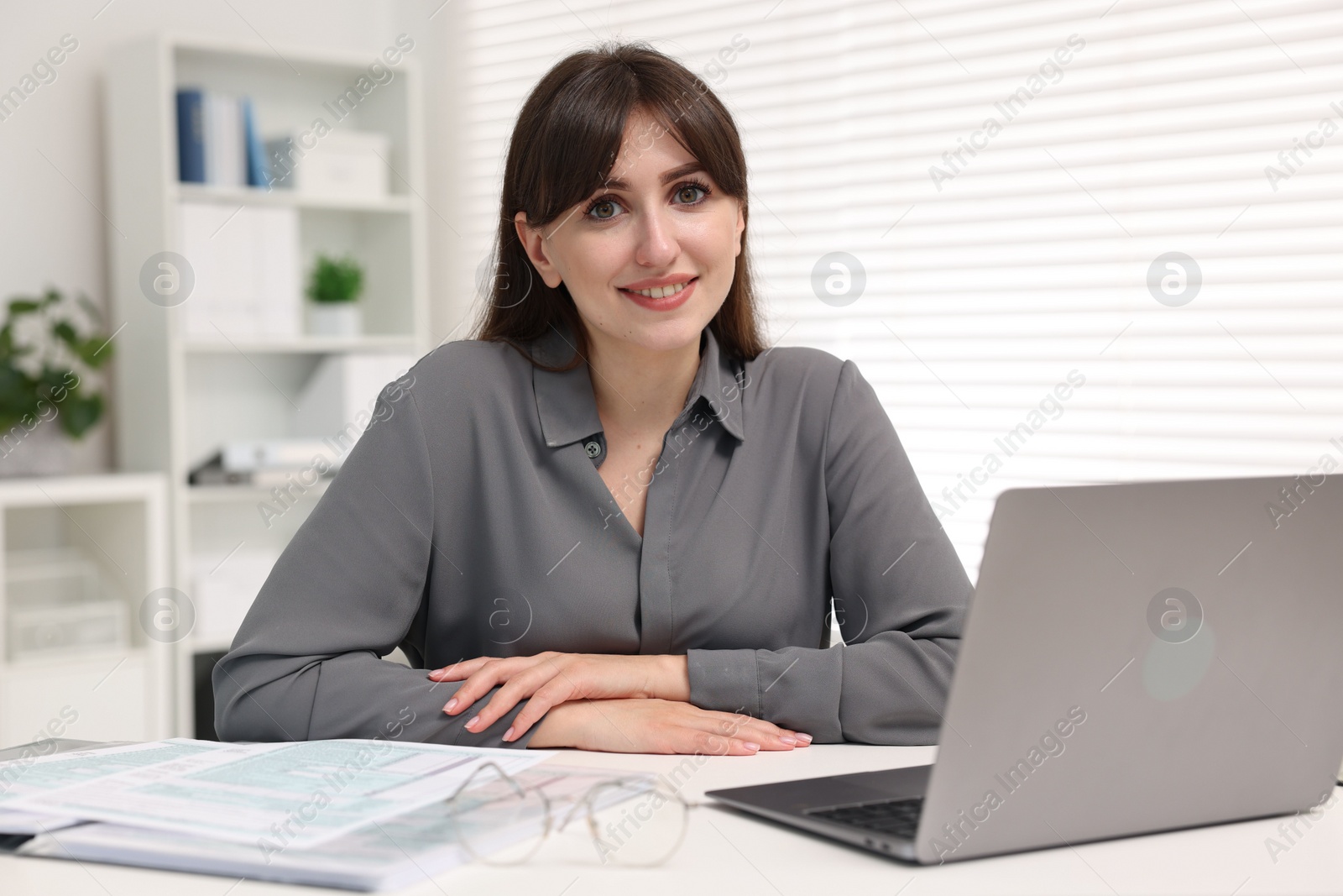 Photo of Portrait of smiling secretary at table in office