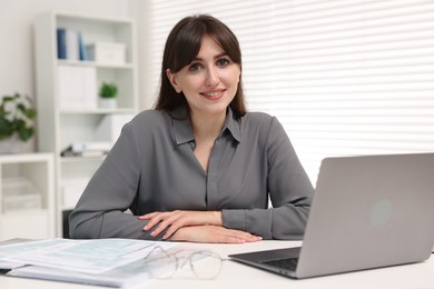 Portrait of smiling secretary at table in office