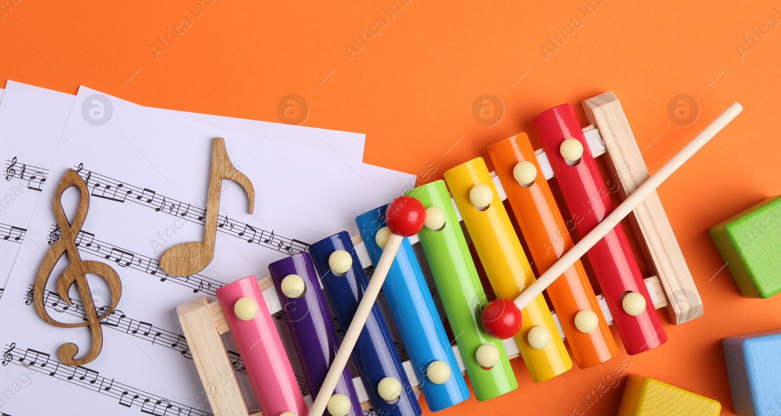 Photo of Tools for creating baby songs. Flat lay composition with xylophone on orange background