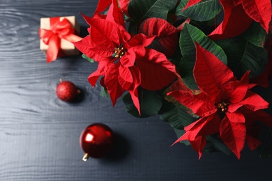 Poinsettia (traditional Christmas flower) with decor and gift on wooden table, top view