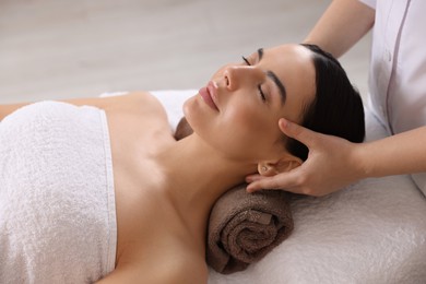 Photo of Young woman enjoying professional massage in spa salon