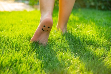 Photo of Teenage girl with smiling face drawn on heel walking outdoors, closeup