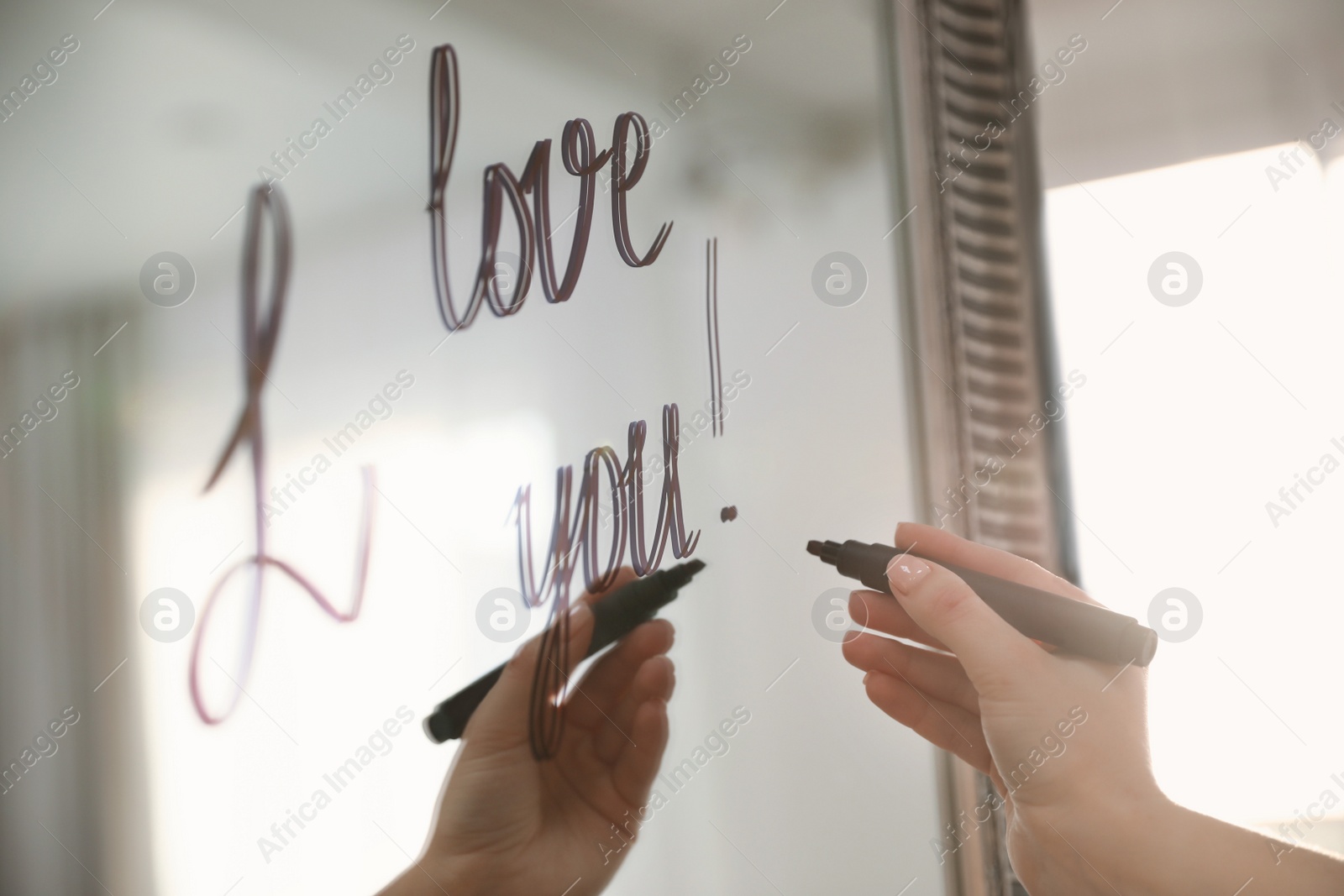 Photo of Woman writing romantic message I Love You on mirror in room, closeup