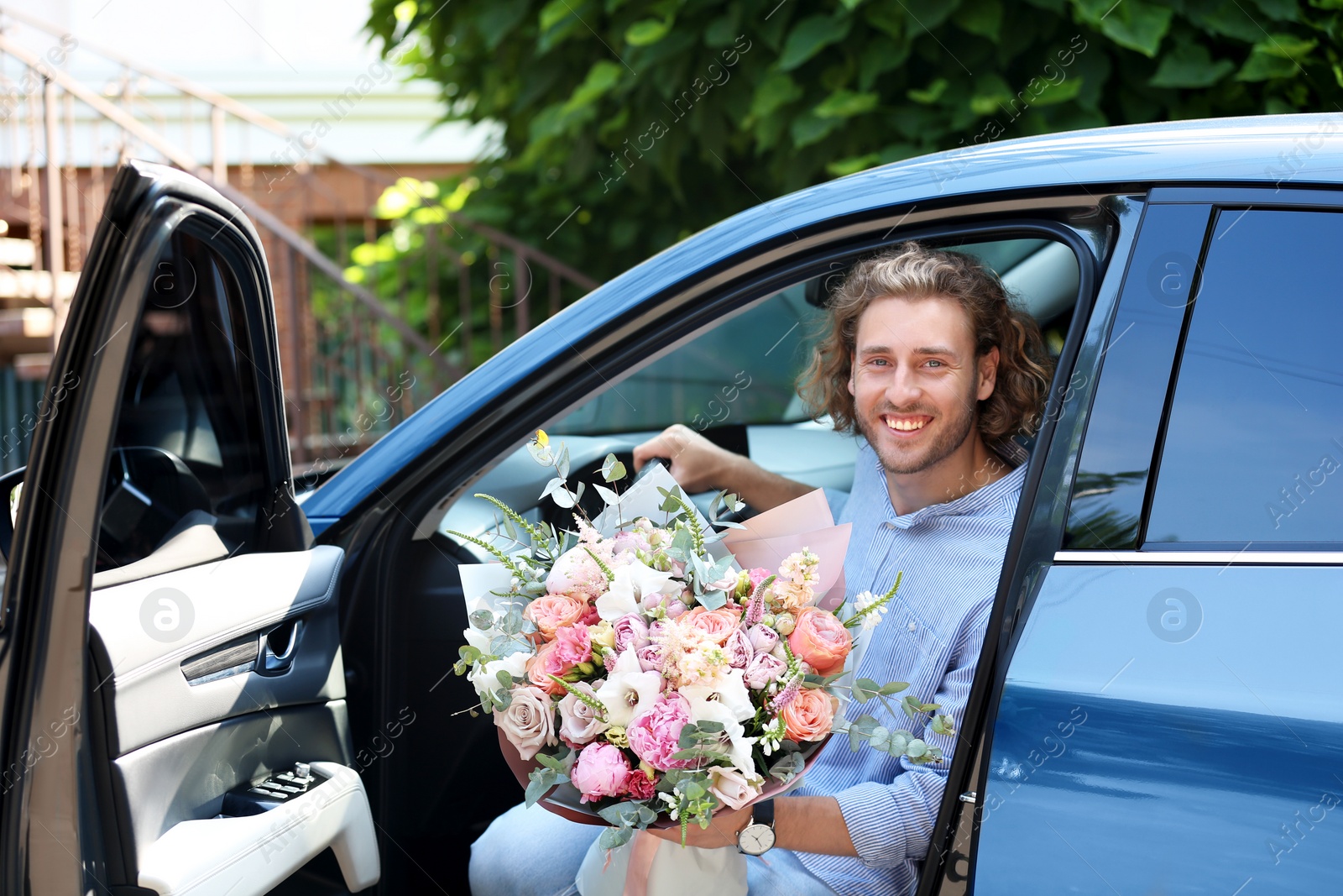 Photo of Young handsome man with beautiful flower bouquet in car