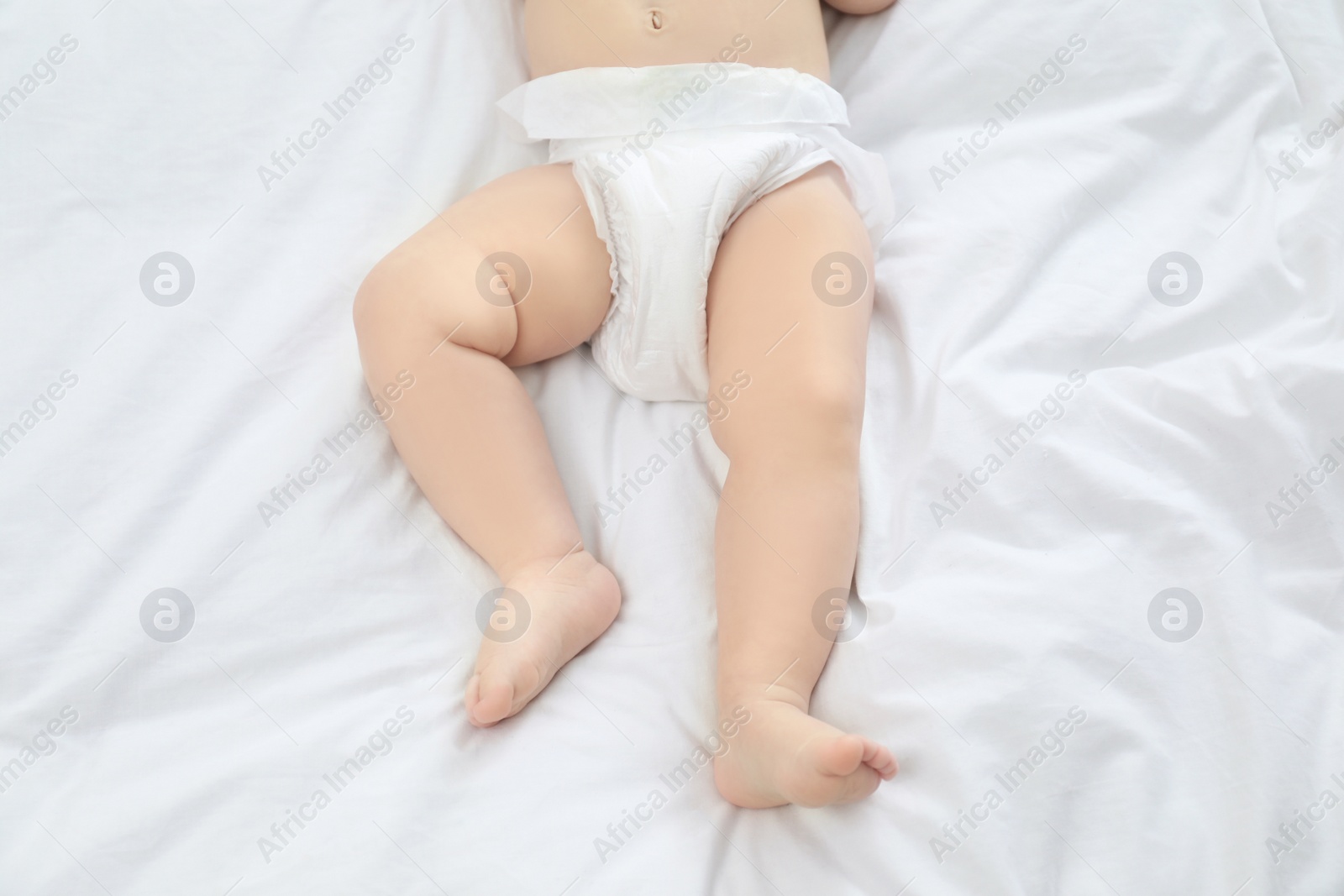 Photo of Cute little baby in diaper on bed, top view