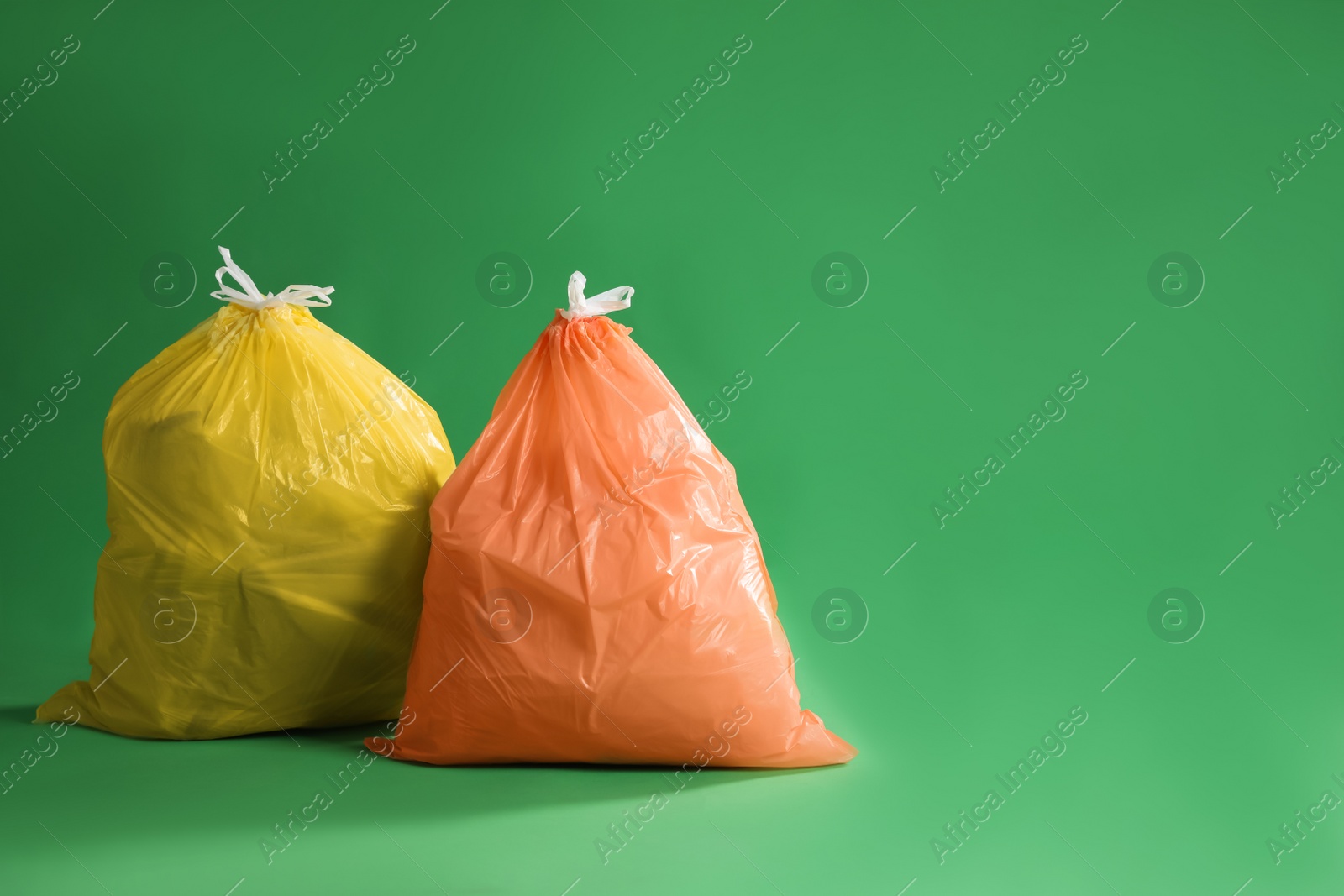 Photo of Trash bags full of garbage on green background. Space for text