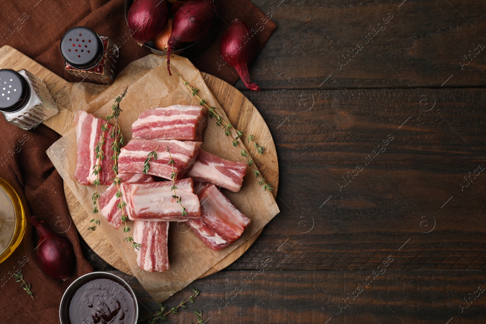 Photo of Flat lay composition with cut raw pork ribs and sauce on wooden table. Space for text