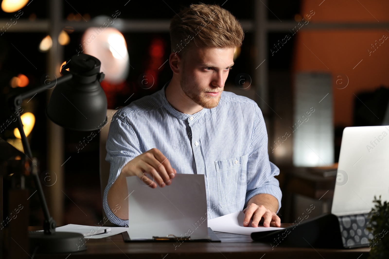 Photo of Young man working in office at night