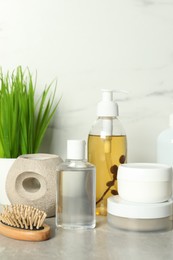 Photo of Brush and personal care products on gray table near white marble wall