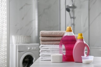 Photo of Stack of folded towels and detergents on white table in bathroom