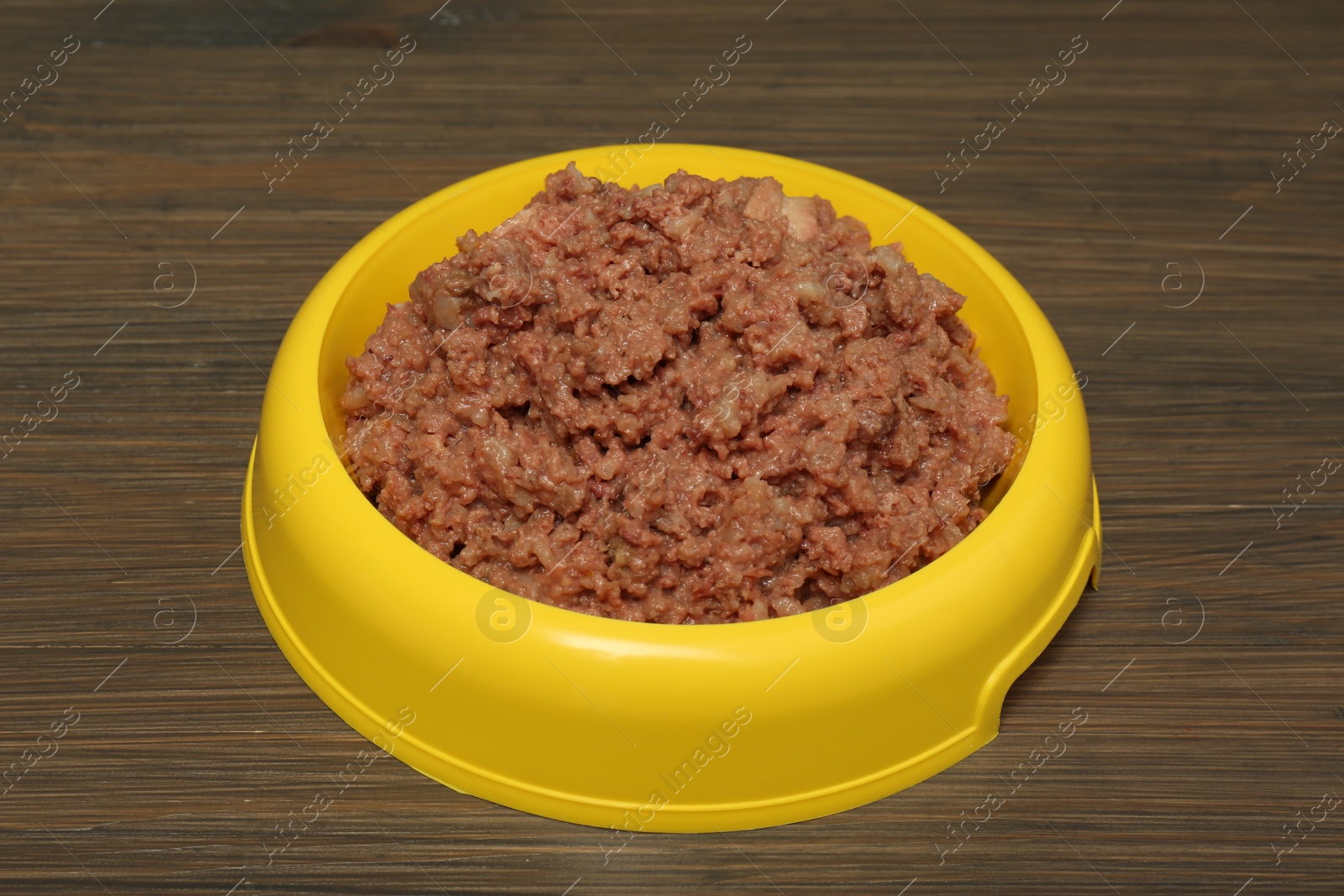 Photo of Wet pet food in feeding bowl on wooden background