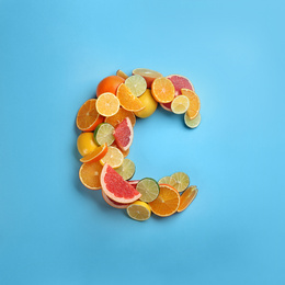 Photo of Letter C made with citrus fruits on light blue background as vitamin representation, flat lay