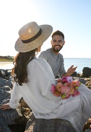 Photo of Happy young couple with flowers on beach. Honeymoon trip