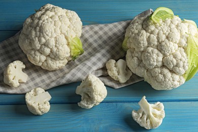 Fresh whole and cut cauliflowers on light blue wooden table
