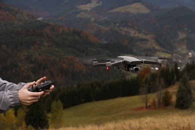 Woman operating modern drone with remote control in mountains, closeup