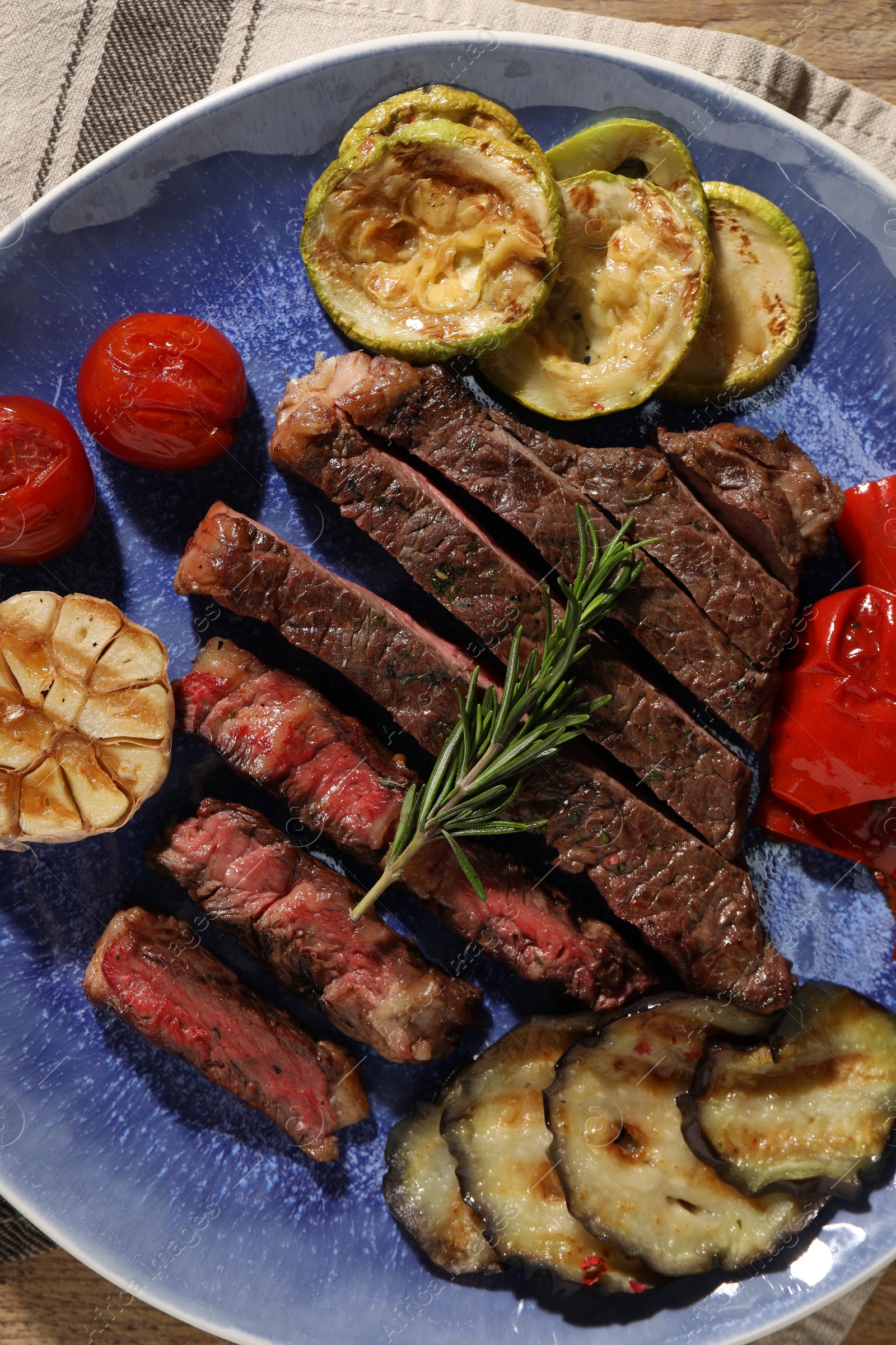 Photo of Delicious grilled beef steak with vegetables and spices on table, top view