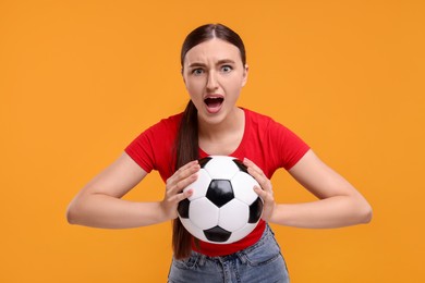 Photo of Excited soccer fan with ball on orange background