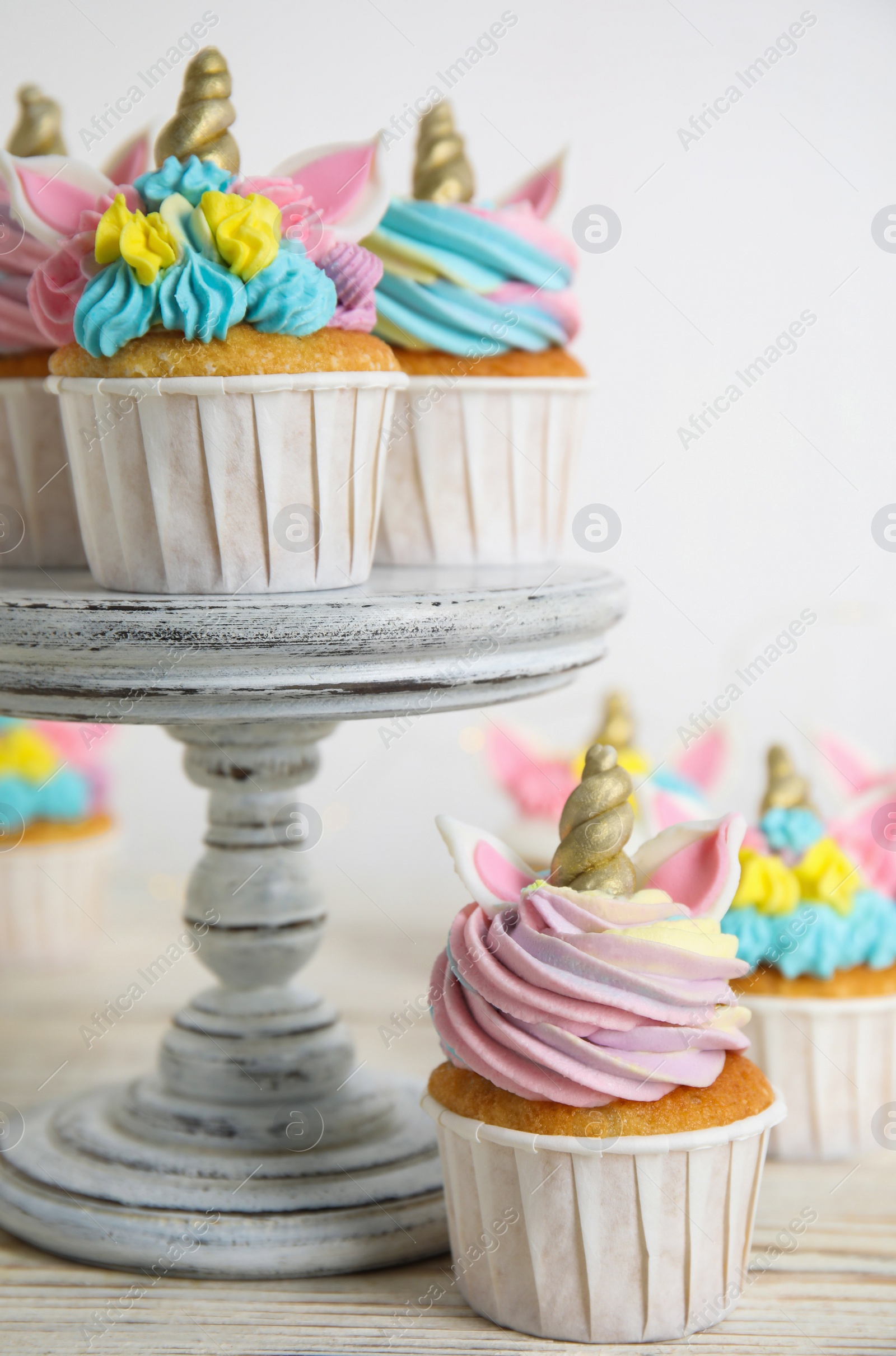 Photo of Cute sweet unicorn cupcakes on white wooden table