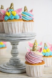 Cute sweet unicorn cupcakes on white wooden table