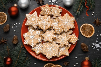 Photo of Tasty Christmas cookies, fir branches and festive decor on black table, flat lay