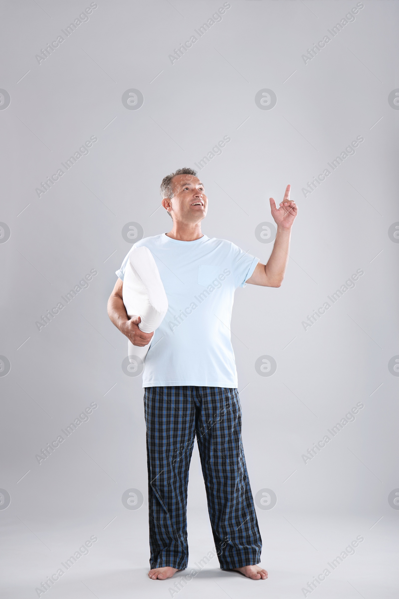 Photo of Man holding soft pillow on light background