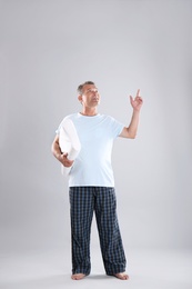 Photo of Man holding soft pillow on light background