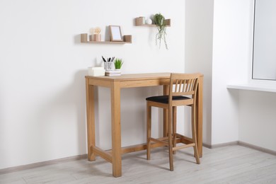 Photo of Comfortable workplace with wooden desk near white wall at home