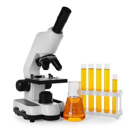 Photo of Laboratory glassware with orange liquid and microscope isolated on white