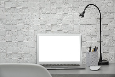 Photo of Laptop on desk against light wall in home office. Comfortable workplace