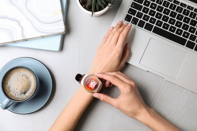 Image of Woman checking mail application in smart watch at table, top view