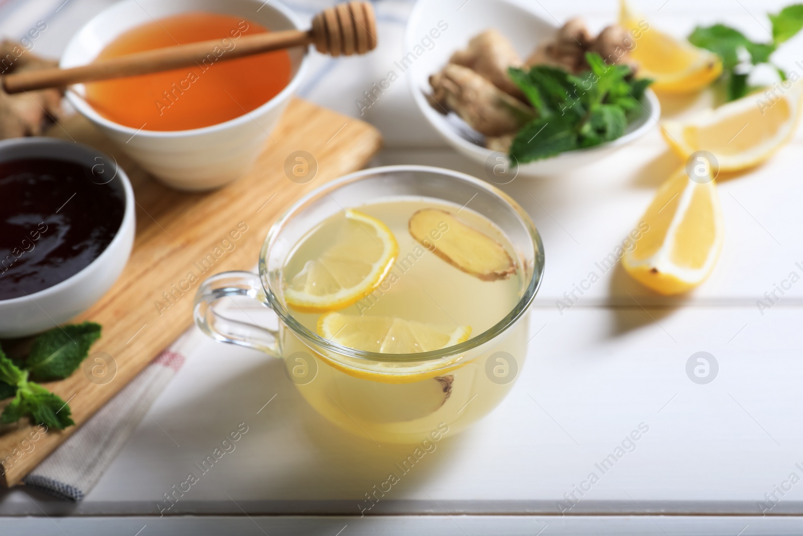 Photo of Delicious ginger tea and ingredients on white wooden table