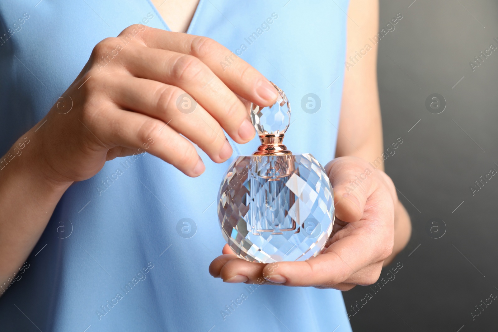 Photo of Woman holding glass perfume bottle, closeup view