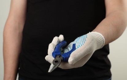 Man with needle nose pliers on light background, closeup