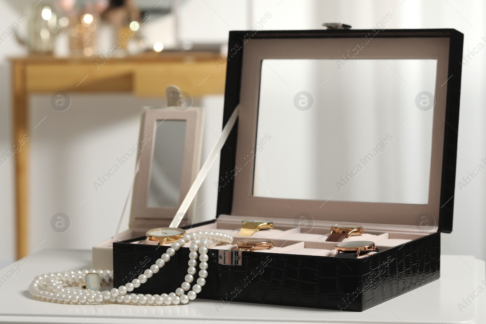 Photo of Jewelry boxes with many stylish wristwatches, accessories and pearl necklace on white table indoors