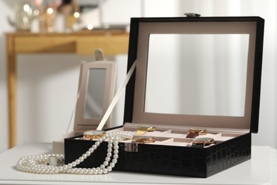 Photo of Jewelry boxes with many stylish wristwatches, accessories and pearl necklace on white table indoors