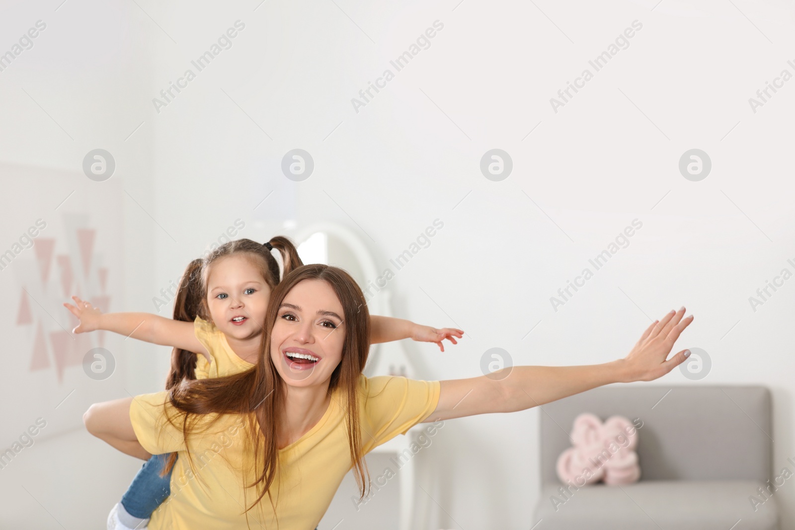 Photo of Young mother with little daughter having fun at home