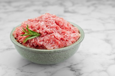 Bowl of raw fresh minced meat with rosemary on white marble table, closeup