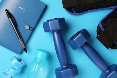 Flat lay composition with dumbbells on light blue background