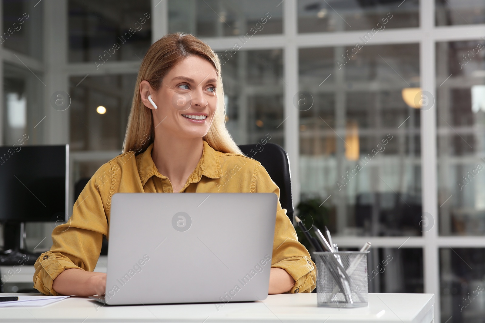 Photo of Woman working on laptop at white desk in office. Space for text